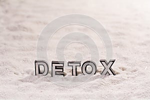 Detox word on white sand