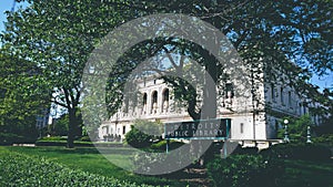 Detroit Public Library in a park surrounded by greenery under a blue sky and sunlight