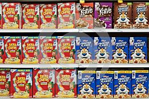 Grocery store shelf with boxes of various brands of breakfast cereal.