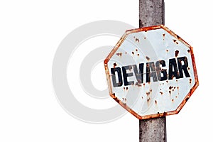 â€œDevagarâ€ in Portuguese, slow or slowly written in a rusty and grungy white and red old weathered road traffic sign