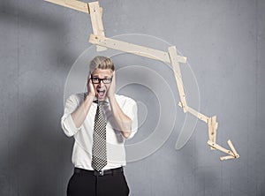 Devastated businessman shouting in front of graph pointing down.