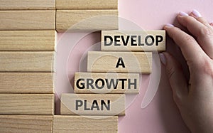 Develop a growth mindset symbol. Wooden blocks with words Develop a growth mindset. Beautiful pink background. Businessma hand.