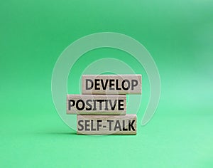 Develop positive self-talk symbol. Concept words Develop positive self-talk on wooden blocks. Beautiful green background. Business