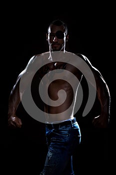 Developed big muscle man with eye patch posing in studio