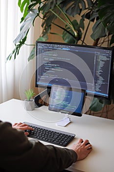 Developer is coding using screen and tablet. Freelancer is working from home