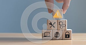 Developer programmer holding a wooden cube with warning triangle sign for notifying error found error and maintenance concept