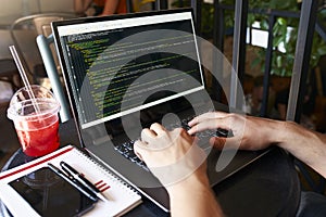 Developer programmer with laptop. Program code and script data on screen. Young freelancer in glasses working on project