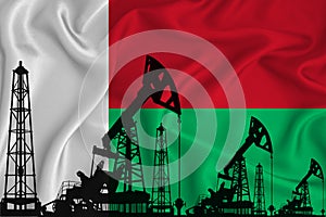 Developing Flag of Madagascar. Silhouette of drilling rigs and oil rigs on a flag background. Oil and gas industry. The concept of