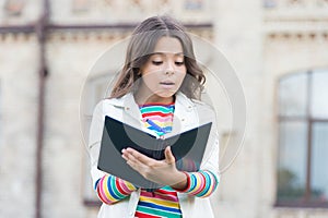 Developing her reading skills. Little girl read book outdoor. Small kid enjoy reading day. Adorable bibliophile. Child photo