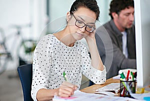 Developing a well thought out plan. a beautiful young woman working at her desk in an office.