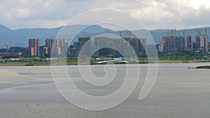 development of city, buildings under construction in modern district on shore of river