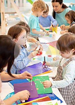 Development learning children in preschool. Children`s project in kindergarten. Group of kids and teacher cutting paper