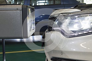 The device for adjusting the light of the headlights stands in front of the car`s headlight