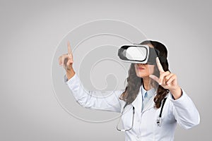 Device for medical education. Female doctor in coat with stethoscope experiencing virtual reality in vr glasses