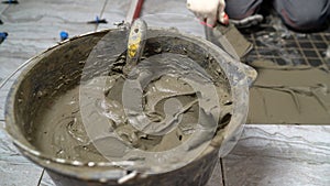 A device for mixing ceramic tile adhesive. Glue bucket. Mixing glue in a bucket. A worker mixes tile adhesive in a