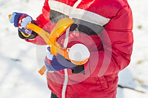 A device for sculpting snowballs in children`s hands against a background of snow. Children`s winter games of snowballs