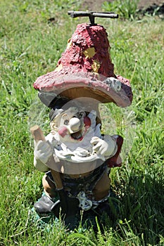 Device for watering a lawn in the form of a gnome with a shovel under the mushroom