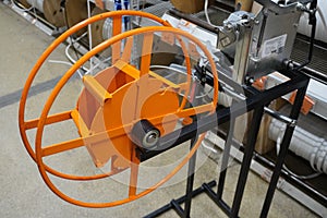 THE DEVICE FOR WINDING A FLEXIBLE ELECTRICAL CABLE INSTALLED IN A BUILDING MATERIALS STORE IS ORANGE. INDUSTRIAL AND CIVIL