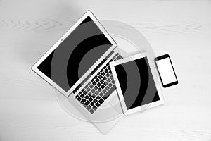 Devices with blank screens on white wooden background,