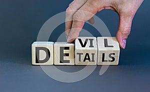 Devil in the details symbol. Businessman hand turns cubes and changes the word `details` to `devil`. Beautiful grey background