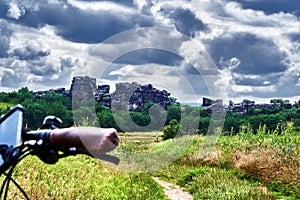 Devil`s Wall near Thale, Germany, behind blurred steering wheel of a bicycle in front of dark clouds, cliffs of limestone in the