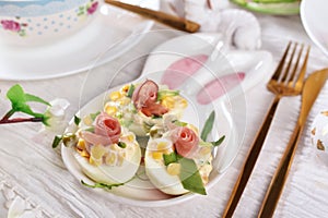 Deviled eggs with ham, peas, corn, chives and mayonnaise on bunny shaped plate for Easter breakfast