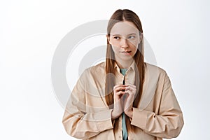 Devious young woman scheming, looking aside at logo with pensive cunning face, steeple fingers, have evil genius plan