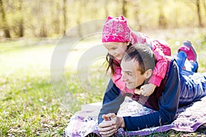 Devoted father and daughter lying on grass, enjoying each others company, bonding, playing, having fun in nature on a bright,