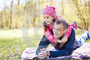 Devoted father and daughter lying on grass, enjoying each others company, bonding, playing, having fun in nature on a bright,