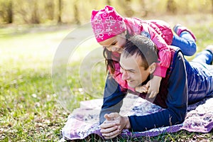 Devoted father and daughter lying on grass, enjoying each others company, bonding, playing, having fun in nature on a bright,