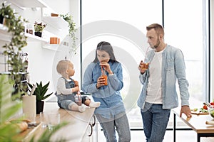 Devoted parents enjoying fresh drinks and looking at baby