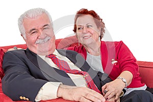 Devoted senior couple seated on a red sofa