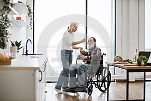 Devoted woman feeds man in wheelchair with fresh healthy salad.