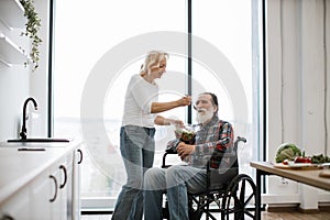 Devoted woman feeds man in wheelchair with fresh healthy salad.