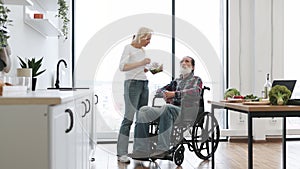 Devoted woman feeds man in wheelchair with fresh healthy salad.