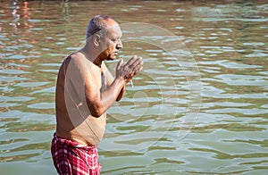 devotee praying after bathing in holy river water at morning from flat angle photo