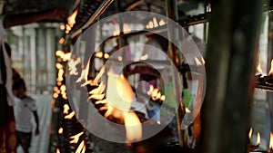 Devotees oil lamps in Buddhist temple as spiritual ritual. Flames flicker on rows of lamps in serene ceremony. People