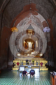 Devotees praying in front of Buddha statue. Htilominlo pagoda. Bagan. Myanmar