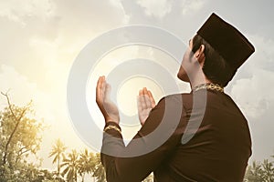 Devout asian muslim man praying with his both hands