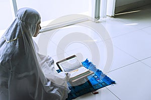 Devout woman reading Quran after doing Salat