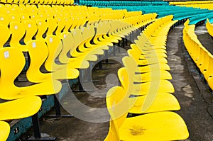 Empty yellow plastic chairs in symmetrical rows in a cricket stadium