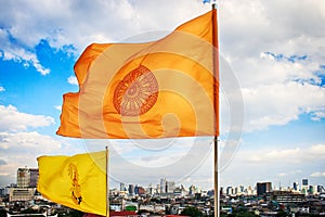 Dharmachakra flag and HM King Bhumibol Adulyadejâ€™s flag on top of the phu khao thong or golden mountain of wat saket, Thailand