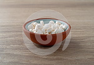 DHEA pills in a bowl on a table side view