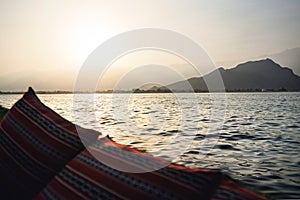 Dhow boat cruise in Musandam Peninsula in Oman at sunset. View from tourist sail ship to mountains and traditional Omani town.