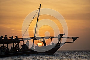 Dhow sailing during sunset in Zanzibar. Dhow is a wooden vessel with a sail, used to transport goods. Mostly used in