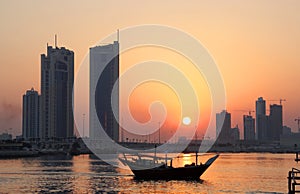 Dhow and Seef skyline during sunset in Bahrain