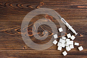 Diabet concept. Sugar and insulin in syringe on dark wooden background photo
