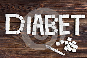 Diabet concept. Sugar and insulin in syringe on dark wooden background photo
