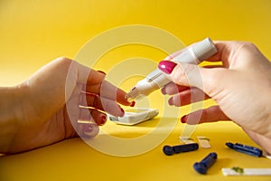 Diabet. Medical equipment. Medical concept. Close up of woman hands on yellow background using lancet on finger to check blood