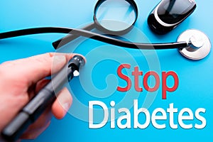 Diabetes concept. Glucometer or Glucose meter, sugar and spoon with words STOP DIABETES on blue background. Healthcare